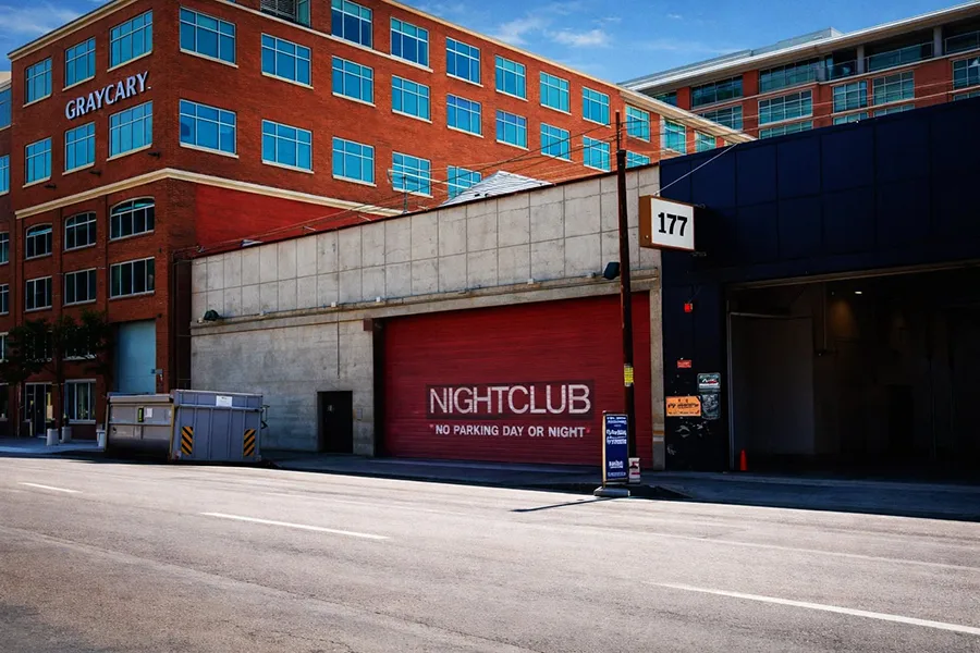 The exterior of Club Townsend, a converted warehouse with a giant red-painted mechanical door reading “NIGHTCLUB: NO PARKING DAY OR NIGHT” and a “177” sign above the main pedestrian entrance.